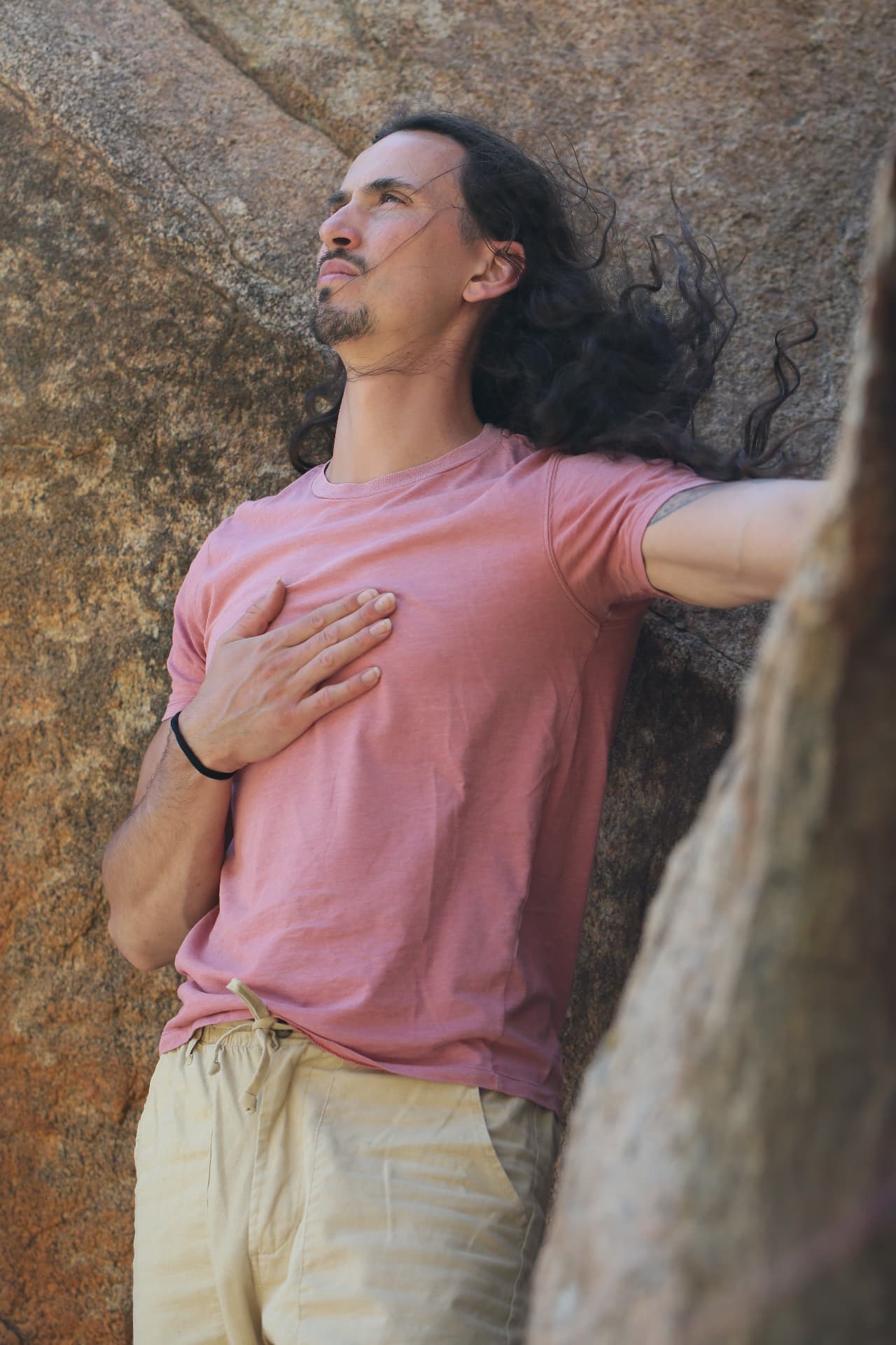 Portrait of Cielo among the rocks, with a hand over his heart